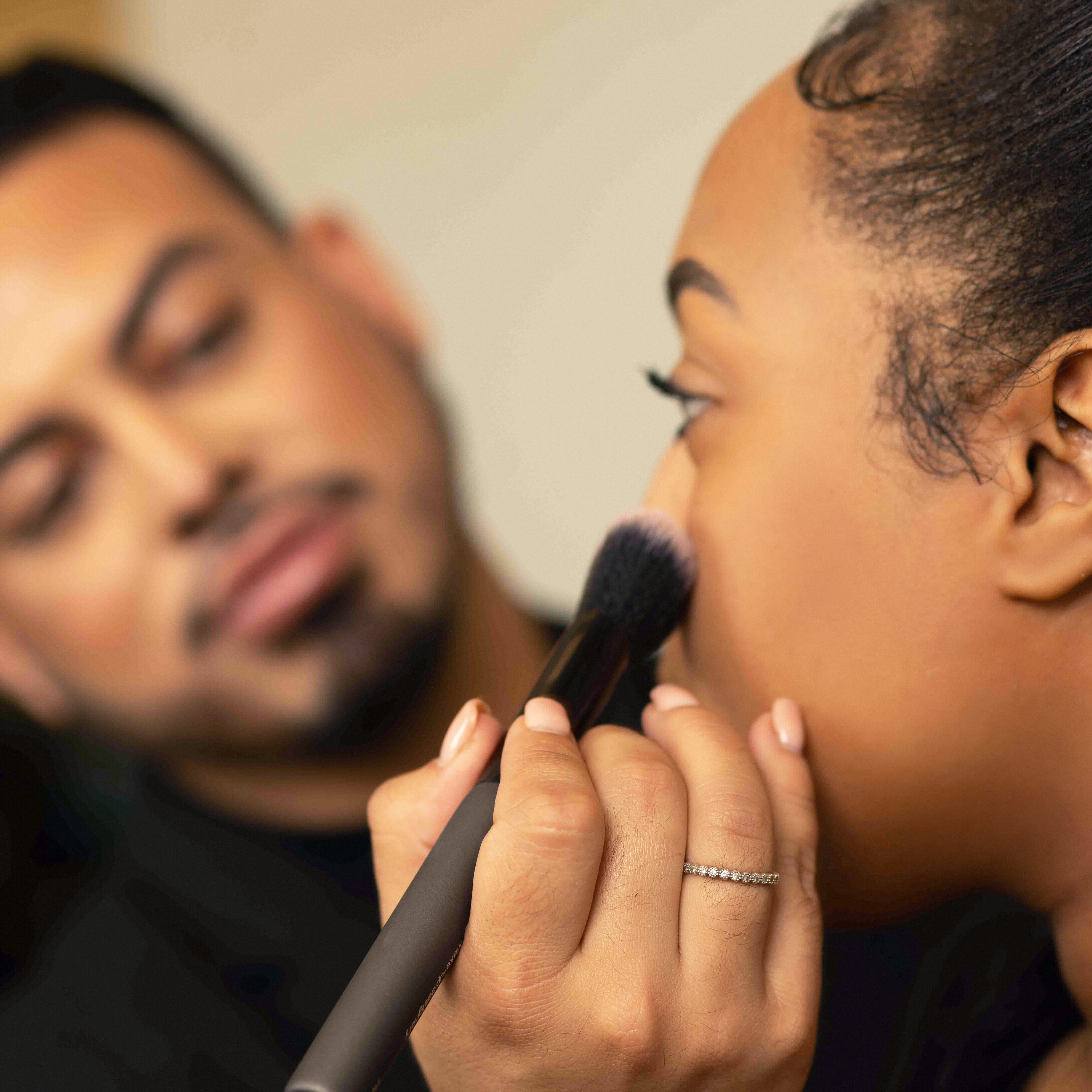 Esthetician school student in an esthetician training program applying make-up to a client